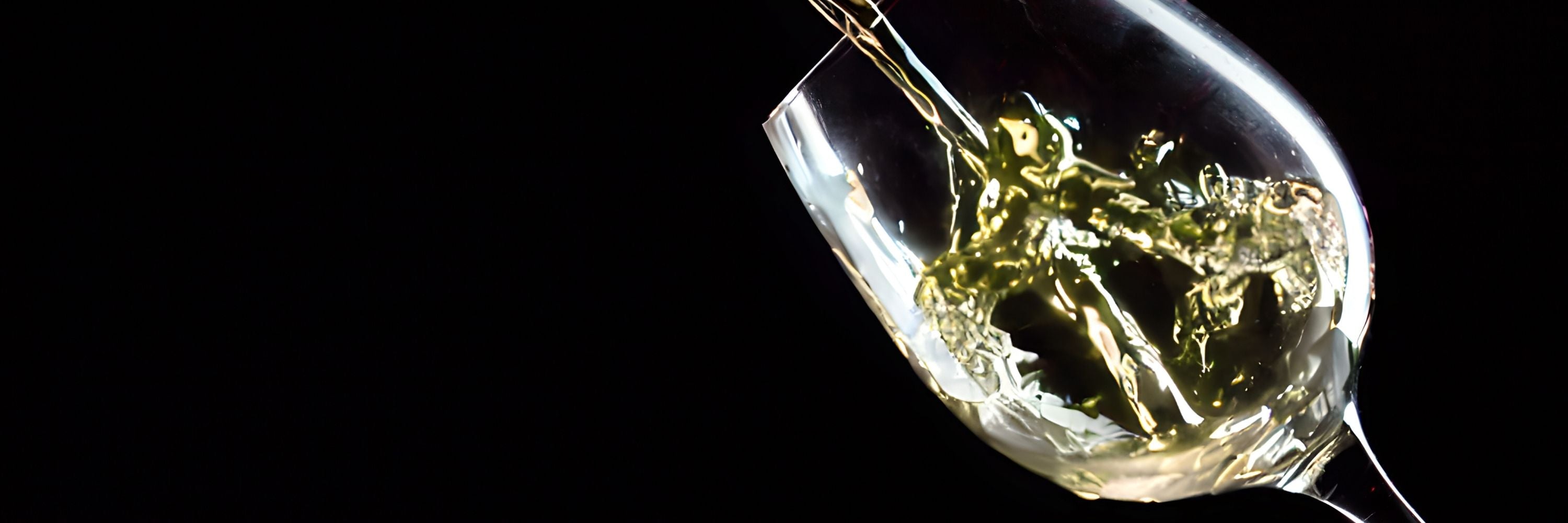 Origine Fra Weißwein im Glas auf dunklem Hintergrund.